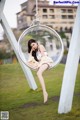 A woman sitting in a hanging chair in a park.