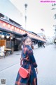 A woman in a plaid coat is walking down the street.