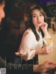 A woman sitting at a table with a glass of wine.