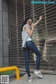 A woman leaning against a metal fence talking on a cell phone.