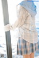 A woman standing by a window looking out at the ocean.