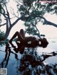 A naked woman laying on the edge of a pool.