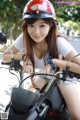 A woman wearing a red helmet sitting on a motorcycle.