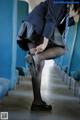 A woman in a school uniform is putting on her shoes.