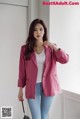 a woman wearing a pink blazer and jeans