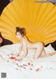 A naked woman laying on a bed with a large yellow shell.