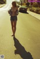 A woman walking down a street with her shadow on the ground.