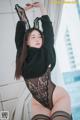 a woman in a black lingerie and stockings posing for the camera