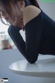 A woman sitting at a table with her hand on her neck.