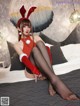 A woman in a red dress and bunny ears sitting on a bed.