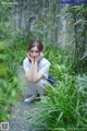 A woman sitting in the middle of a lush green forest.