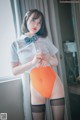 A woman in a white shirt and orange panties posing for a picture.
