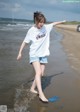 A woman walking on the beach with her arms outstretched.