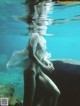 A naked woman in a white dress is submerged in the water.